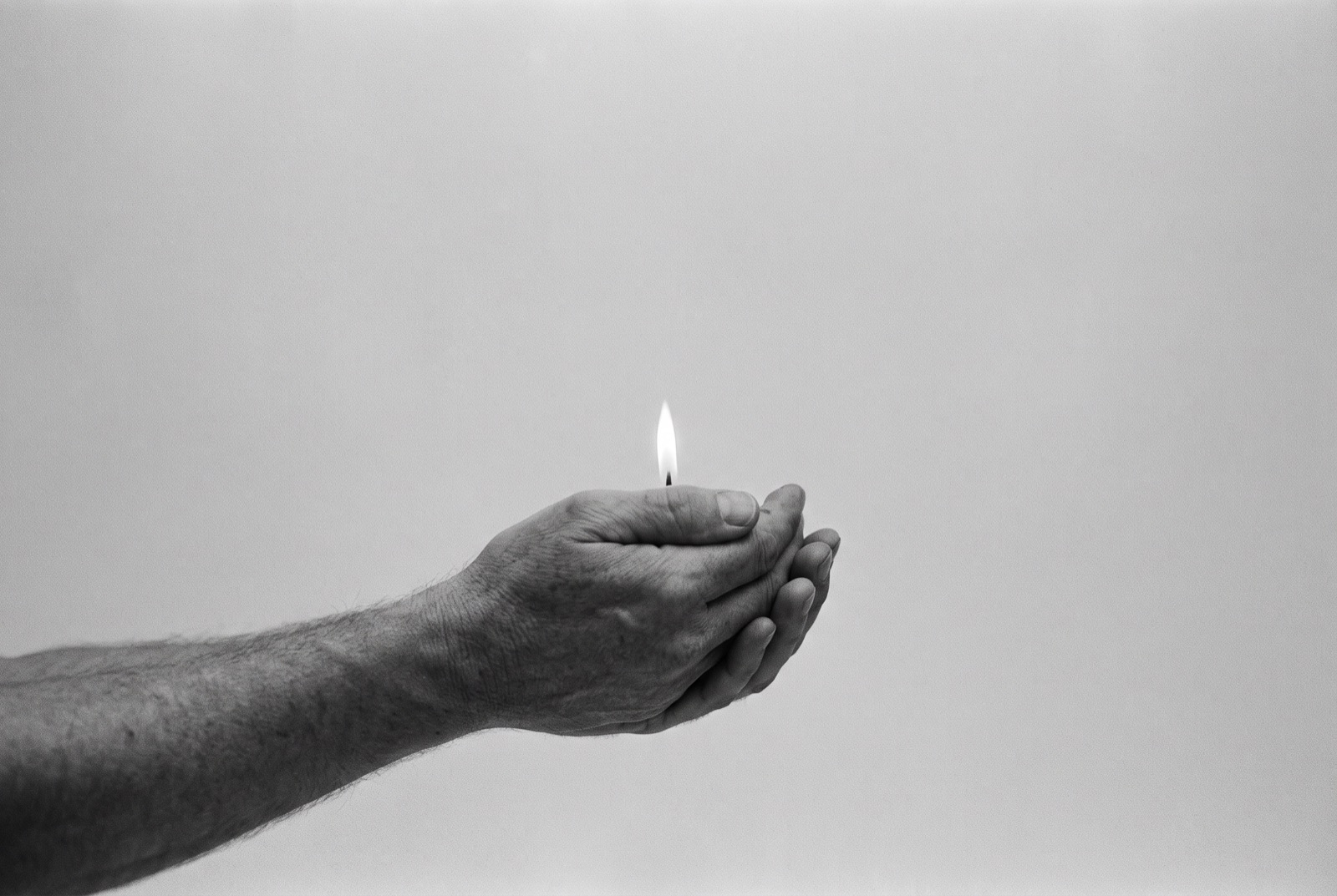 Cupped hands holding a single flame